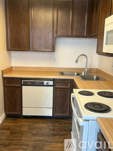 A kitchen with wooden cabinets and a white dishwasher.