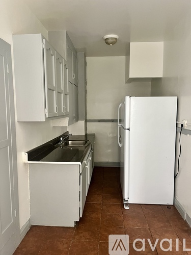 A kitchen with white cabinets and a white fridge.