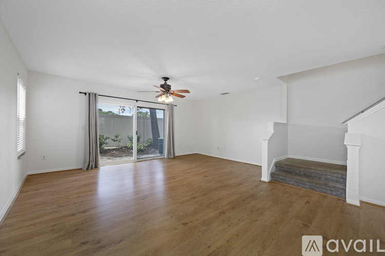 A spacious room with wooden floors and a ceiling fan.