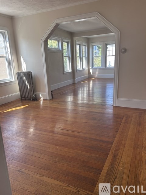 A room with wooden floors and a window with a radiator.