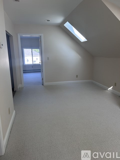 A spacious room with a skylight and a door leading to a balcony.