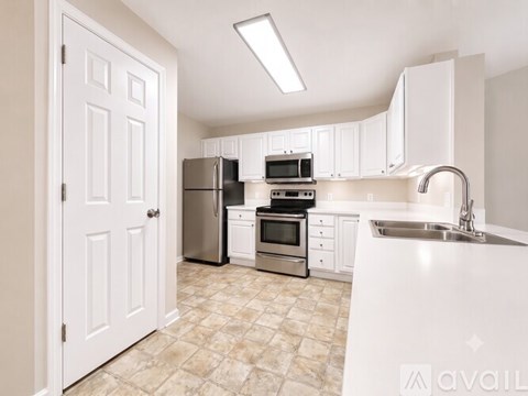 A kitchen with white cabinets and a tiled floor.