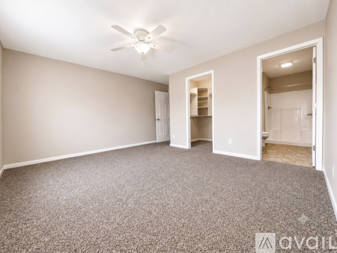 A spacious room with a ceiling fan and carpeted floor.