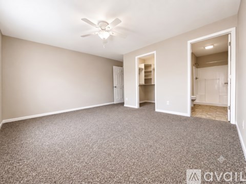 A spacious room with a ceiling fan and carpeted floor.
