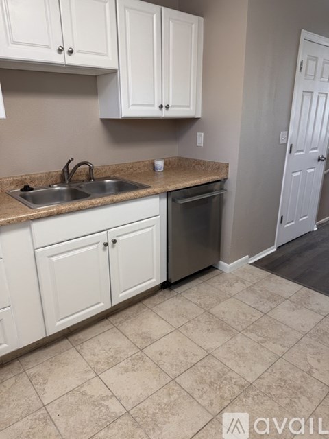 A kitchen with white cabinets and a beige tile floor.