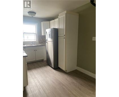 A kitchen with a refrigerator and a sink.