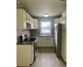 A kitchen with white cabinets and a black counter top.
