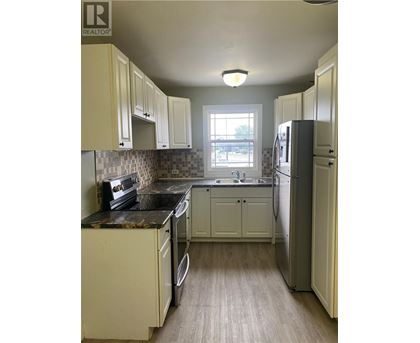 A kitchen with white cabinets and a black counter top.