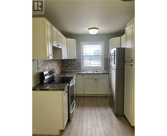 A kitchen with white cabinets and a black counter top.