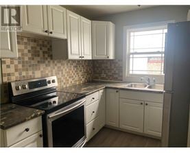 A kitchen with white cabinets and a black stove top oven.