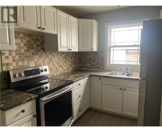 A kitchen with white cabinets and a black stove top oven.