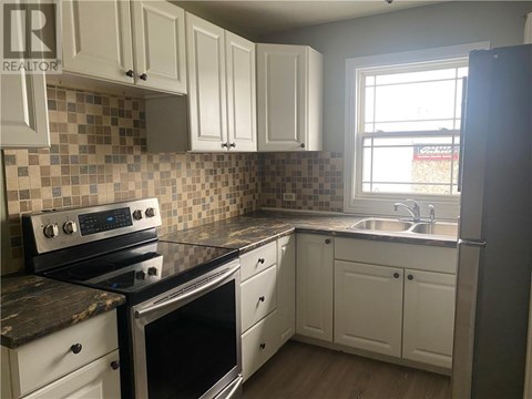 A kitchen with white cabinets and a black stove top oven.
