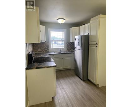 A kitchen with a refrigerator, cabinets, and a counter.