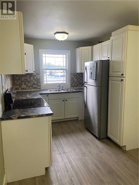 A kitchen with a refrigerator, cabinets, and a counter.
