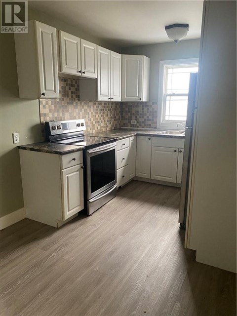 A kitchen with white cabinets and a tile backsplash.