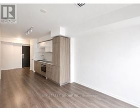 A spacious room with a kitchenette and wooden flooring.