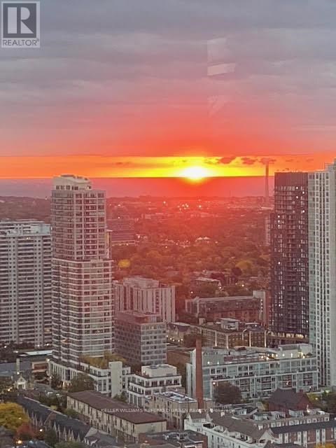 A cityscape with buildings of various heights and a sunset in the background.