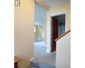 A hallway with a staircase leading to a bedroom.