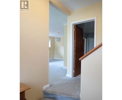 A hallway with a staircase leading to a bedroom.