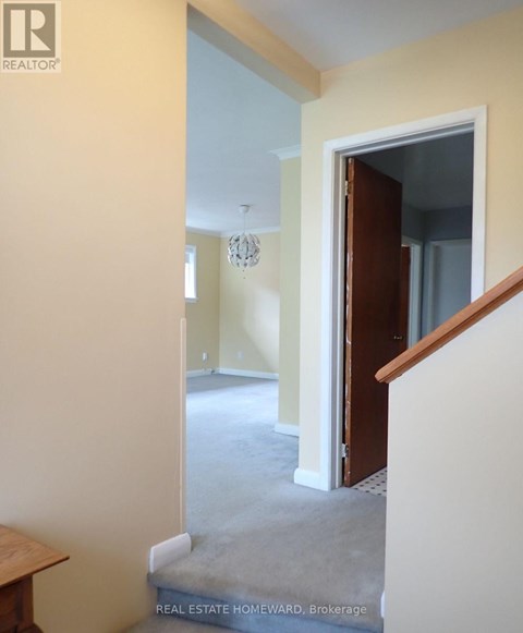 A hallway with a staircase leading to a bedroom.