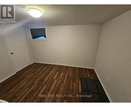 A room with wooden flooring and a window with a view of the sky.