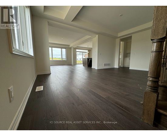 A spacious room with wooden flooring and a large window.
