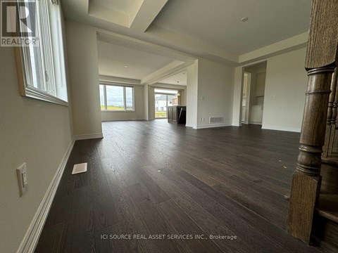 A spacious room with wooden flooring and a large window.
