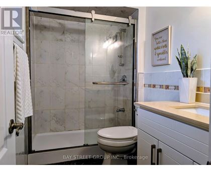 A bathroom with a toilet, a sink, and a glass shower door.