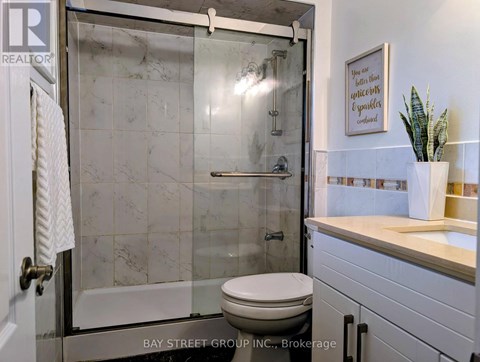 A bathroom with a toilet, a sink, and a glass shower door.