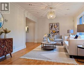 A well-lit, spacious living room with a chandelier, a sofa, a coffee table, and a side table.