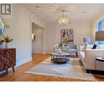 A well-lit, spacious living room with a chandelier, a sofa, a coffee table, and a side table.