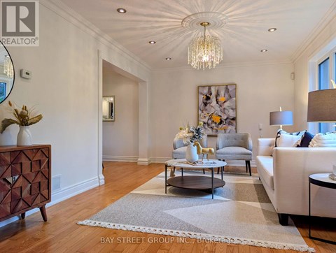 A well-lit, spacious living room with a chandelier, a sofa, a coffee table, and a side table.
