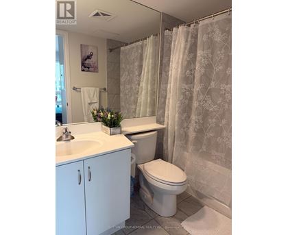A white bathroom with a floral shower curtain.