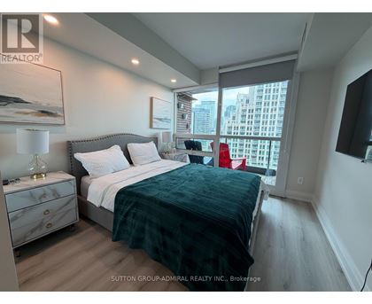 A bedroom with a bed, nightstand, and a window overlooking a cityscape.