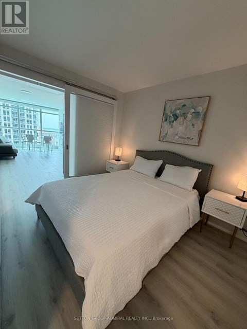 A bedroom with a large bed and a painting on the wall.