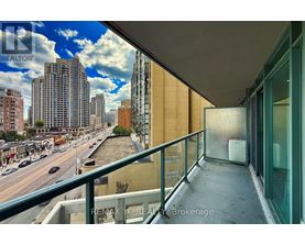 A balcony overlooks a city street with buildings and cars.