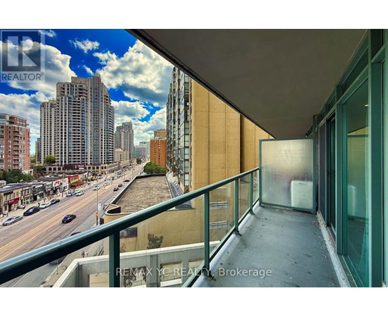 A balcony overlooks a city street with buildings and cars.