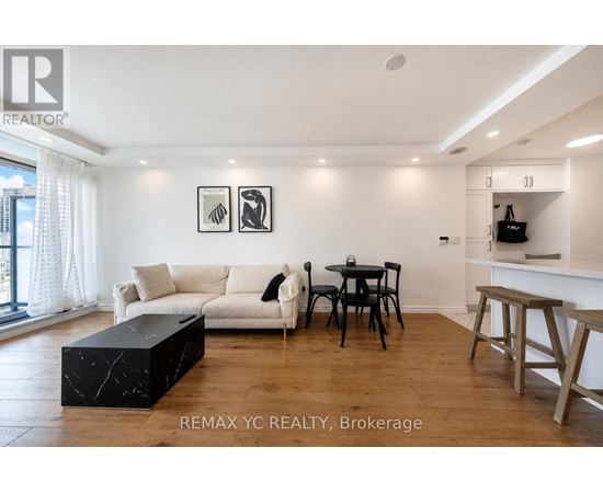 A living room with a white couch, a black coffee table, and a dining table with chairs.