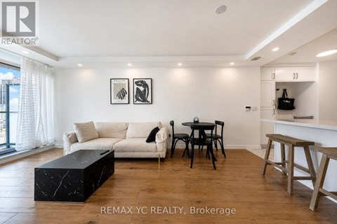 A living room with a white couch, a black coffee table, and a dining table with chairs.