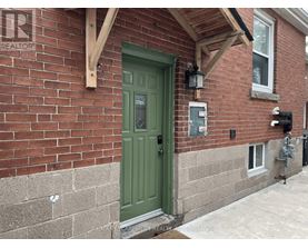 A green door is on the left side of a brick house.