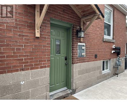 A green door is on the left side of a brick house.