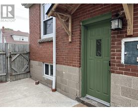 A green door is on the right side of a brick house.