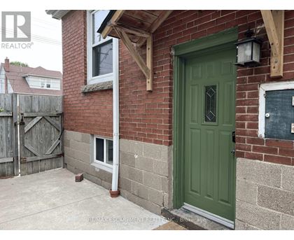 A green door is on the right side of a brick house.