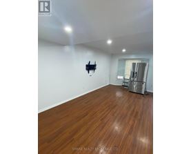A room with wooden flooring and a flat screen TV mounted on the wall.