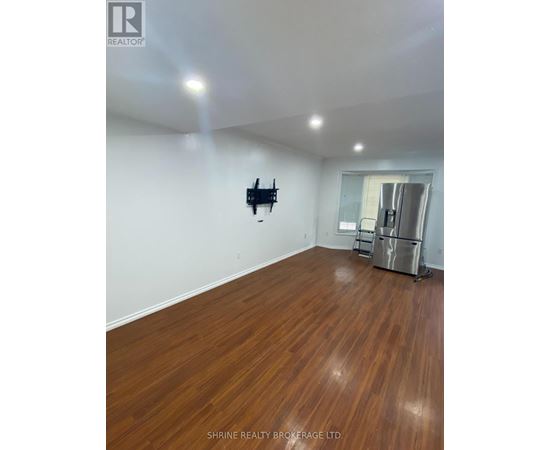 A room with wooden flooring and a flat screen TV mounted on the wall.