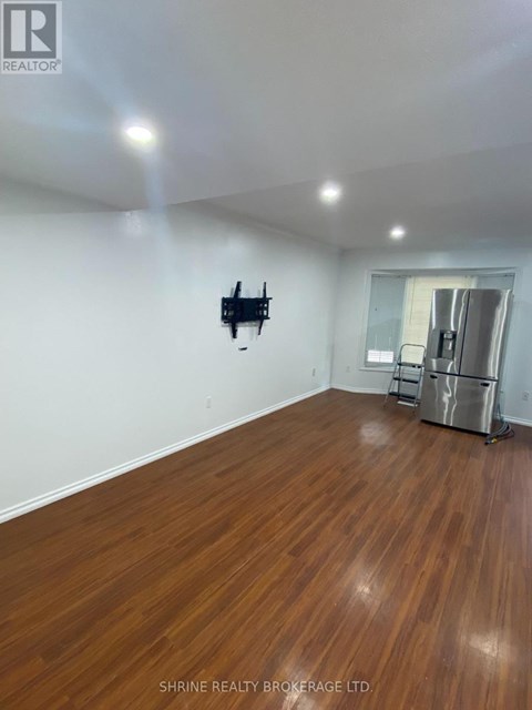A room with wooden flooring and a flat screen TV mounted on the wall.