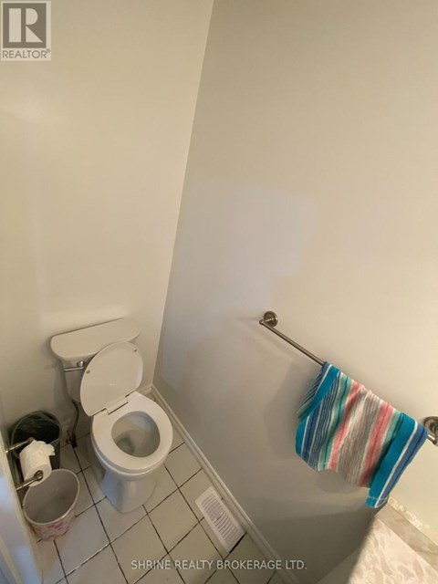 A white toilet with a white lid and a white trash can with a white trash bag in a white bathroom.