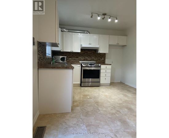 A kitchen with white cabinets and a stone backsplash.