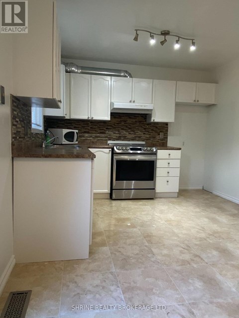 A kitchen with white cabinets and a stone backsplash.