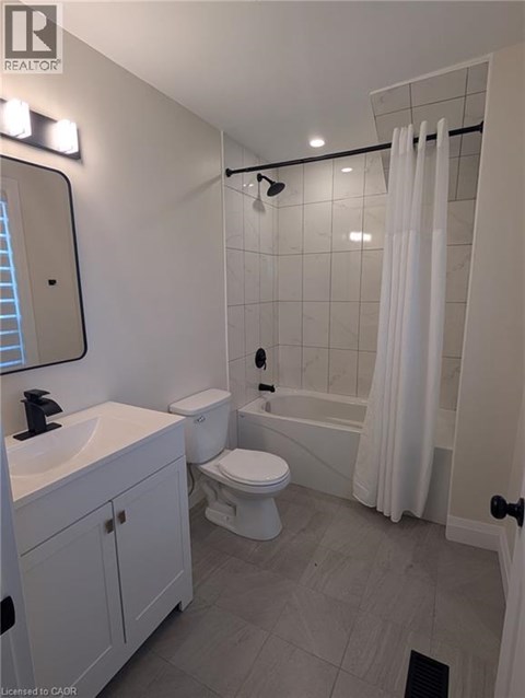 A white bathroom with a toilet, sink, and shower.